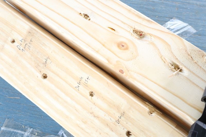 Pine boards with bullet holes and handwritten labels indicating which ammo with each hole.