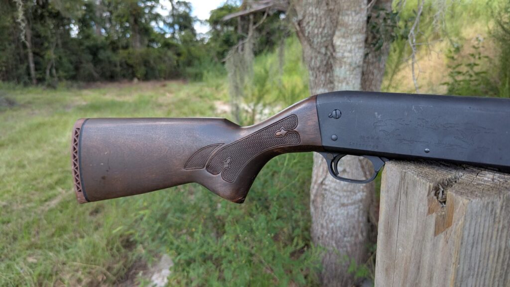 A black shotgun with a wooden stock is shown from the top