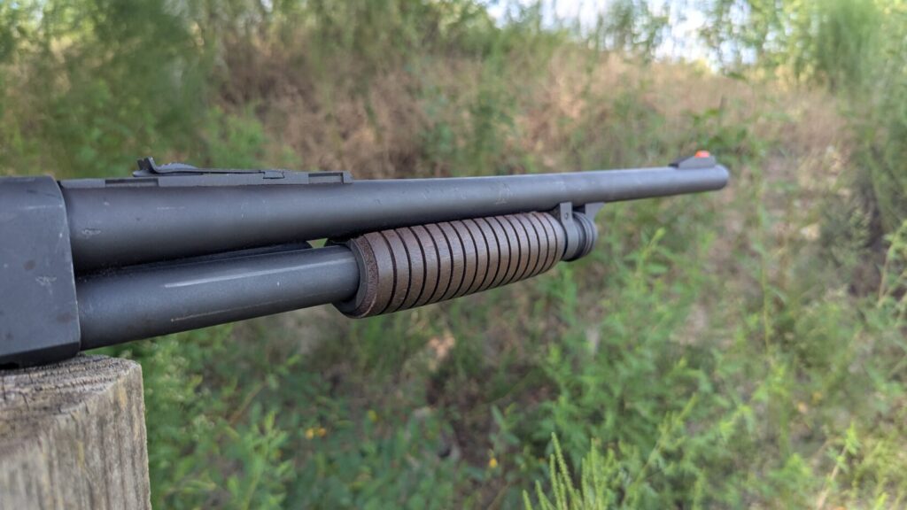  A side view of a shotgun with a dark wood stock and a black barrel