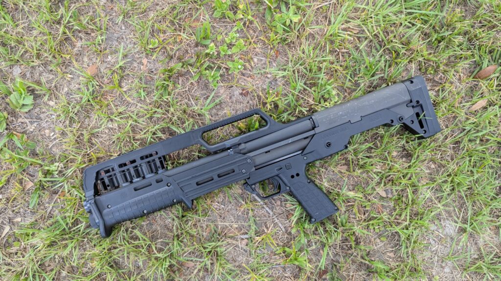 A top-down view of a black KelTec KS7 shotgun on a grassy surface.