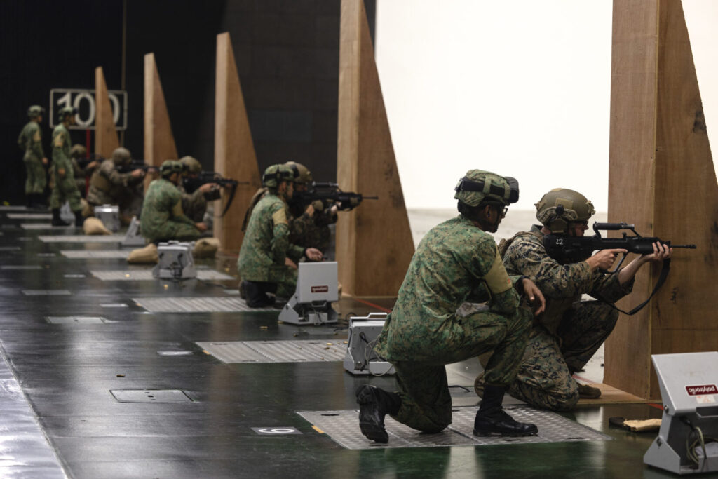 Singapore Army soldiers with 3rd Battalion Singapore Guards, 7th Singapore Infantry Brigade observe U.S. Marines with Marine Rotational Force-Southeast Asia (MRF-SEA), I Marine Expeditionary Force, fire Singaporean Assault Rifle 21 service rifles on a 100-meter range during Exercise Valiant Mark 2022 at the Multi-Mission Range Complex on Pasir Laba Camp, Singapore, Dec. 2, 2022. Valiant Mark is an annual, bilateral training exercise designed to enhance interoperability, build mutual defense capabilities, and strengthen military-to-military relationships between the U.S. Marine Corps and Singapore Armed Forces. MRF-SEA is an operational model developed by Marine Corps Forces Pacific that postures scalable I Marine Expeditionary Forces west of the International Date Line, conducts a series of planned subject matter experts exchanges, and advances security objectives shared with our Allies and Partners. (U.S. Marine Corps photo by Sgt. Ryan H. Pulliam)