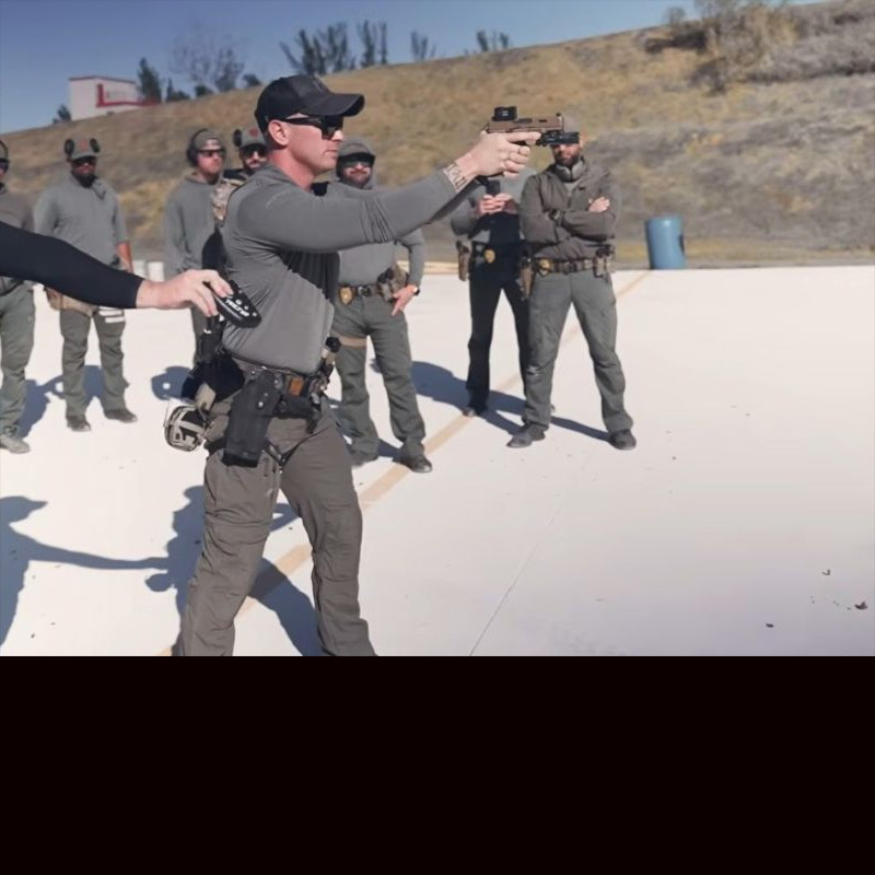Instructor Rick Crawley on the range, fires a handgun at a target. 