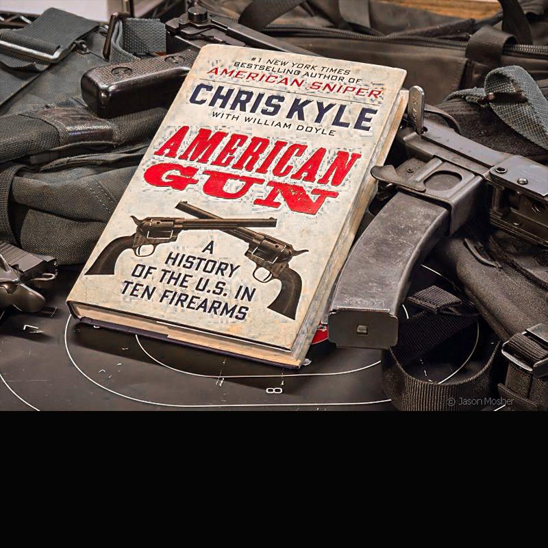 A book called American Gun laying on several guns against a dark background.