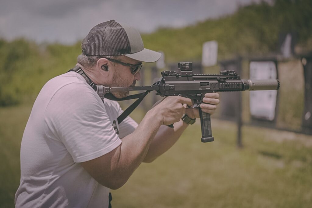 A man holds a firearm at a gun range
