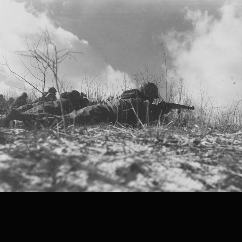 A US Marine laying on the ground, shooting a rifle during the battle of Chosin Reservoir