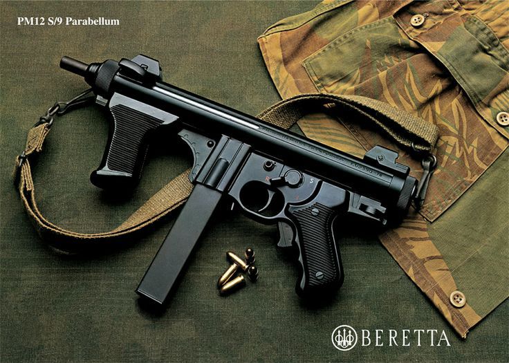 close-up studio shot of a black Beretta PM12S/9 submachine gun with a sling, resting on a green-and-brown camouflage jacket. Two rounds of 9mm ammunition are on the surface nearby.