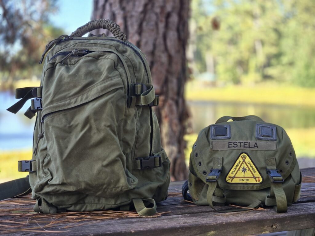 An olive drab 3 day assault pack and a butt pack with a triangular patch