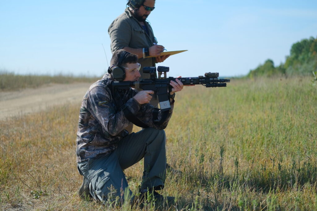 man fires a rifle from the kneeling position using his knee as a brace