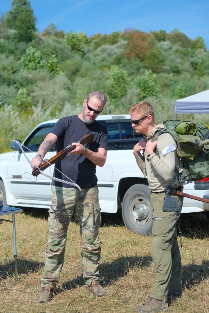 instructor reviews how to use and shoot a primitive crossbow with a competitor
