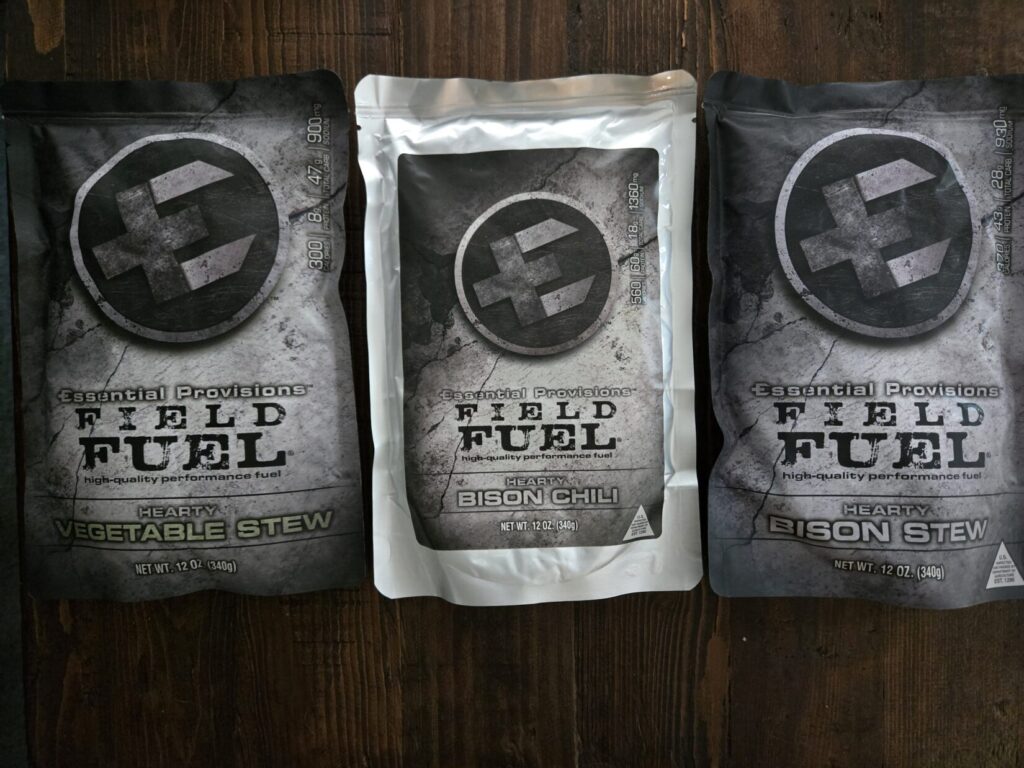 three packets of emergency food on a wooden backdrop