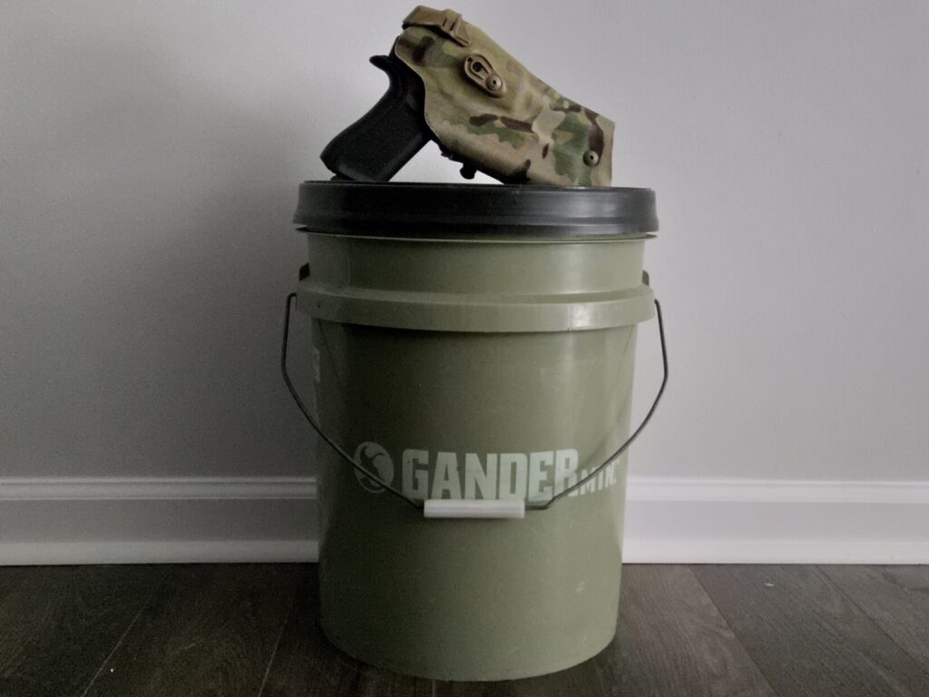 A glock 45 in a Safariland holster on top of a 5 gallon bucket kit