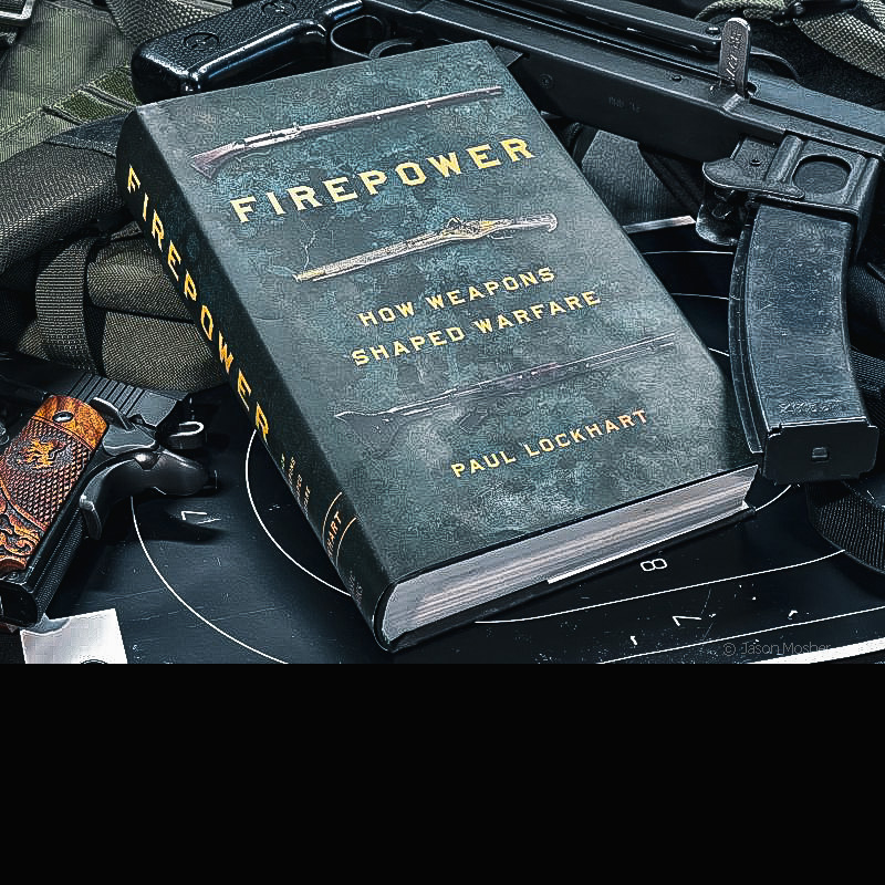 A book called Firepower, sitting on top of several guns against a dark background.