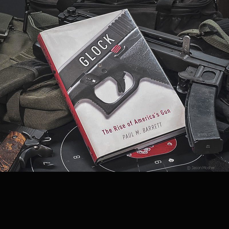 A book called Glock' The Rise of America's Gun laying on several guns with a dark background.