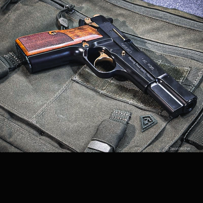 A black handgun with wood grips on a green bag. 