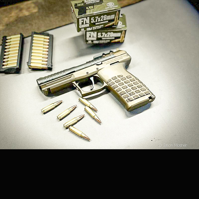 KelTec PR57 on a grey surface with two stripper clips beside it and some loose ammo below it. 