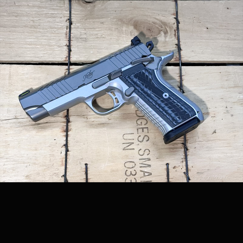 A stainless and grey aluminum handgun lay on a wood box. 