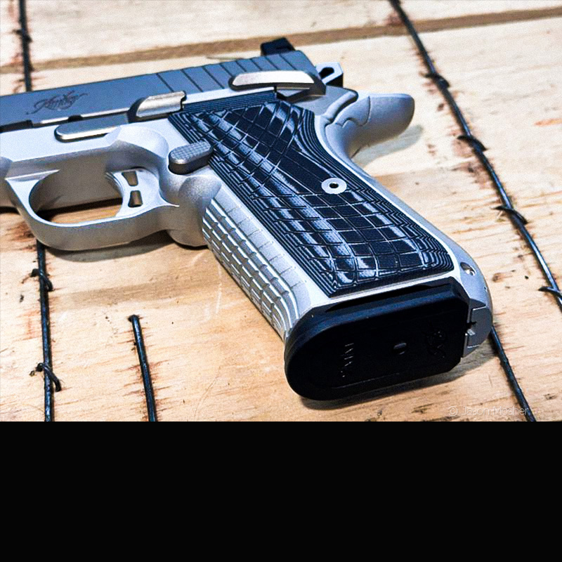 The grip portion of Kimber KDS9c with dark grey grips on a wood box. 