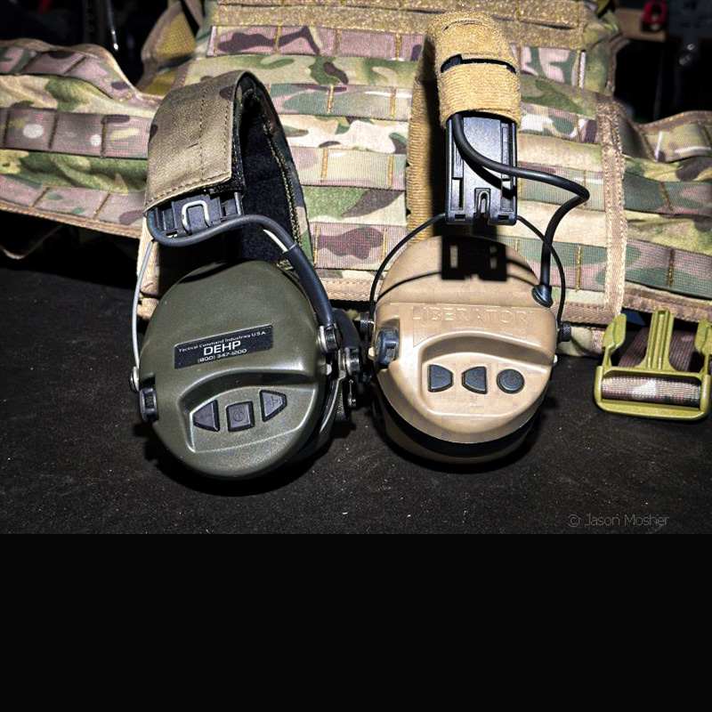 A green pair of electronic earmuffs on the left and a brown pair on the right with a camo vest behind them.