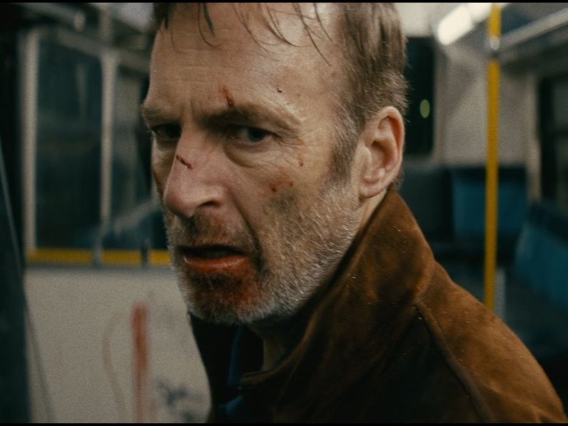 A person standing in a bus with scrapes and scratches on their face.