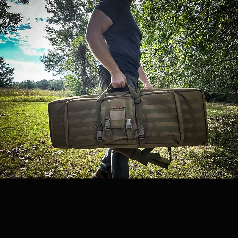 A person carrying a brown rifle case by their side as they walk. 