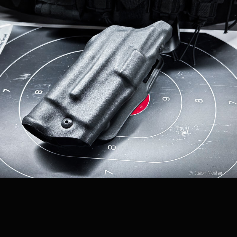 A black holster laying on a target with a red bullseye in the center.