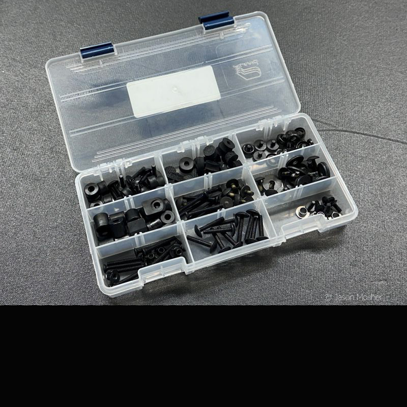 A clear storage container with dividers in it, separating small screws. 