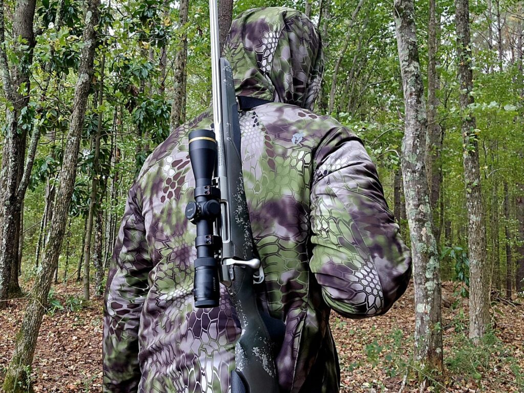 A man in camouflage with a slung rifle over his shoulder