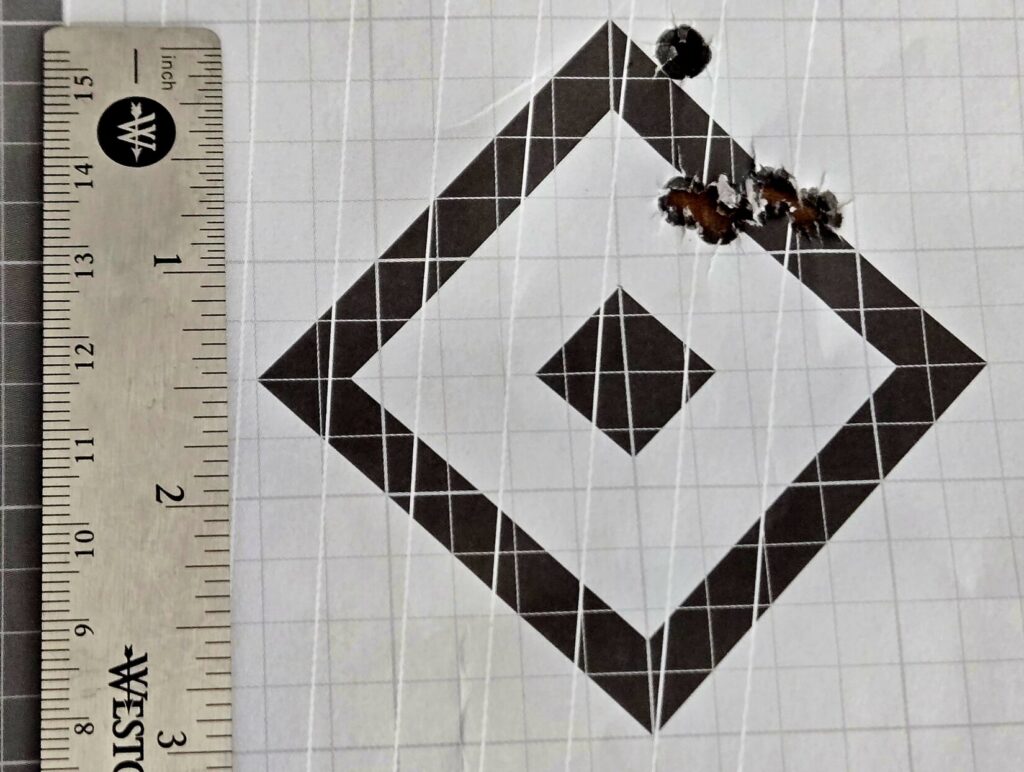 A rifle target showing 4 shots in a horizontal pattern with one flier