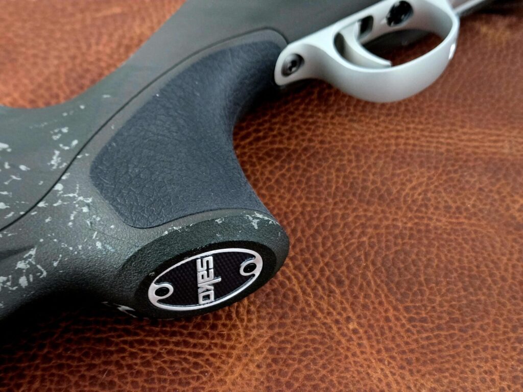 The pistol grip of a rifle on top of a leather background