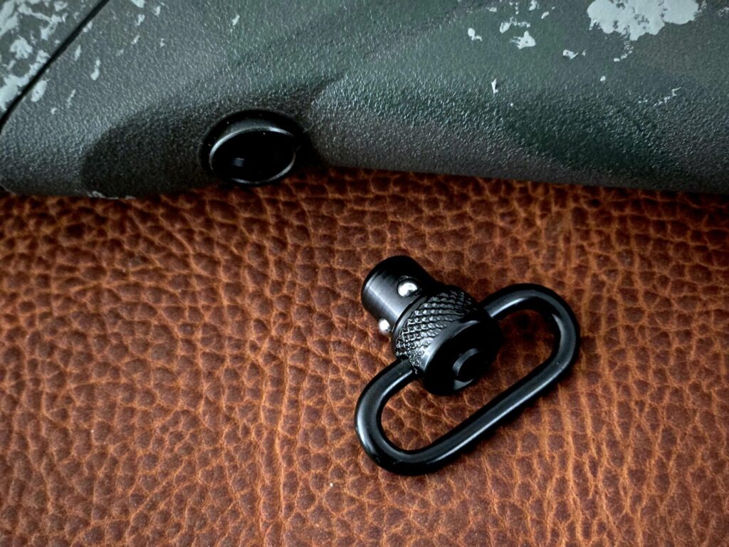 A QD cup and a QD sling swivel on top of a leather background
