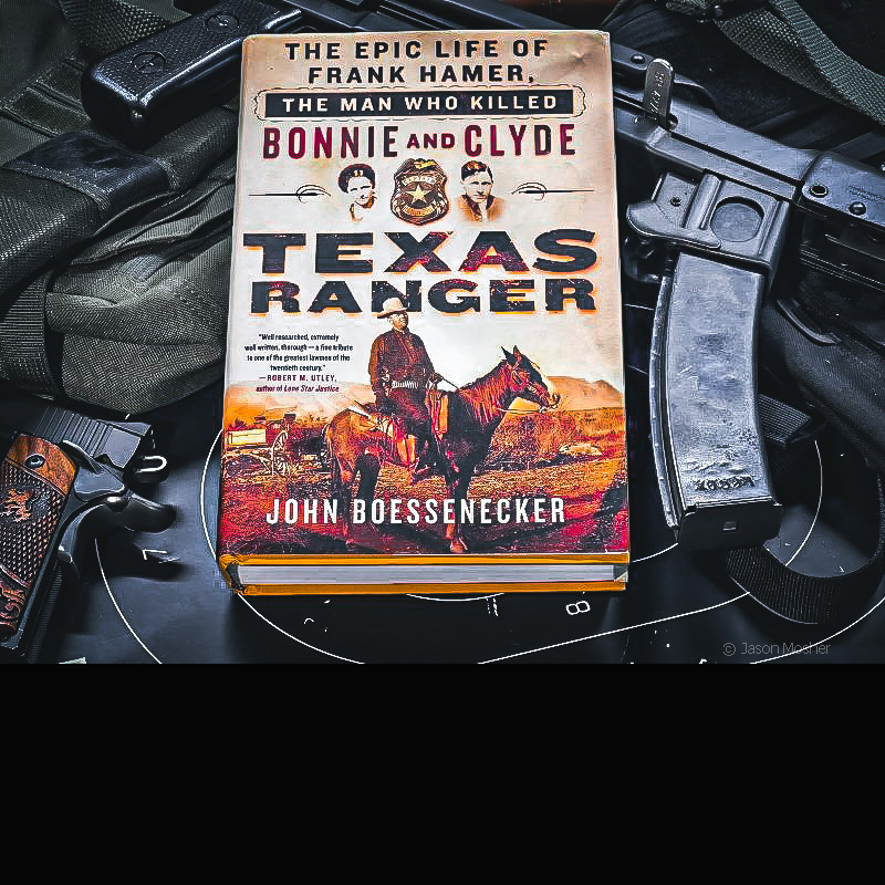 A book called Texas Ranger laying on top of several guns with a dark background.