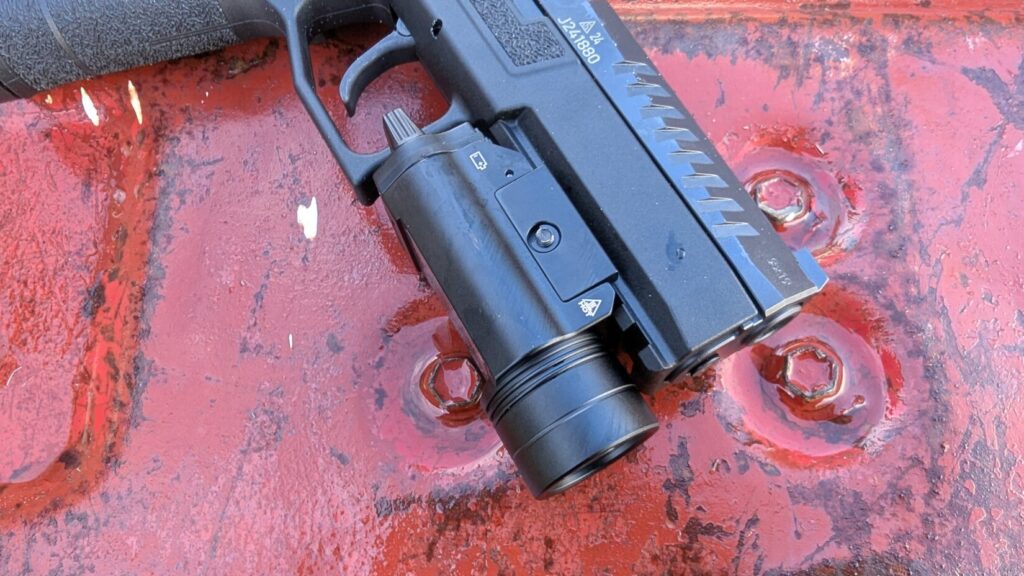 A profile view of a black, polymer-frame pistol with the Braun tactical weapon light mounted on the rail.