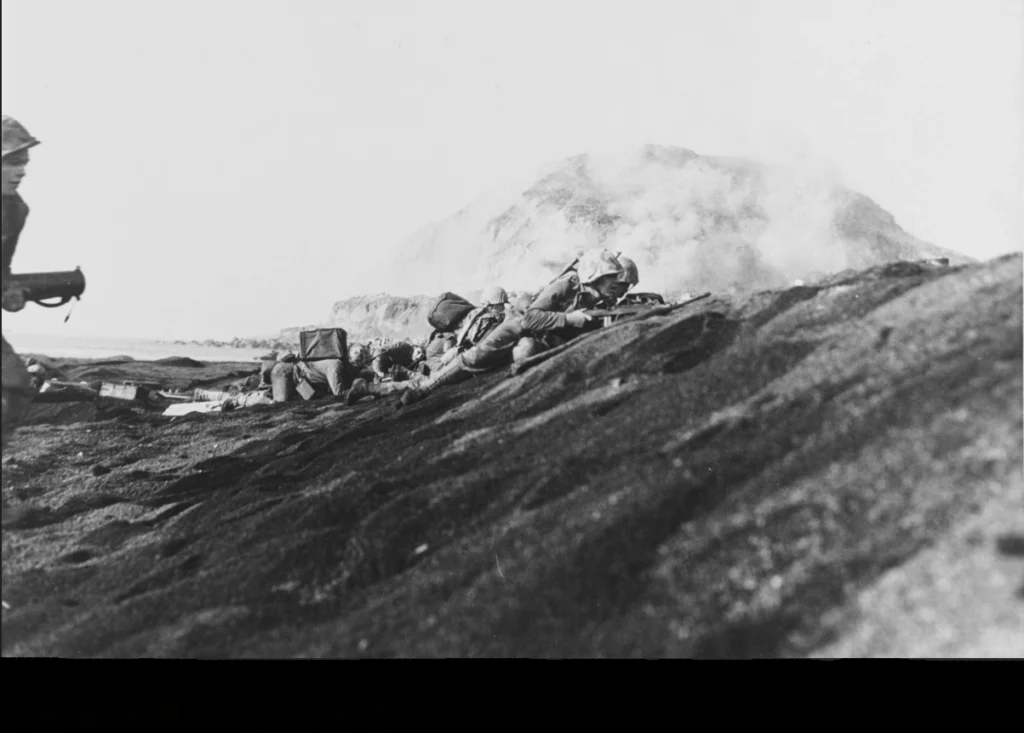 US Marines on Iwo Jima's volcanic ash beach with Mount Suribachi in the background.