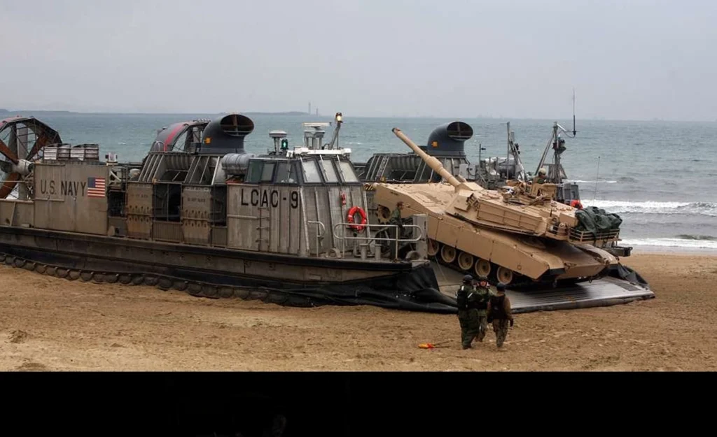 A US Marine M1A1 tank rolling off a US Navy Landing Craft, Air Cushion hovercraft.