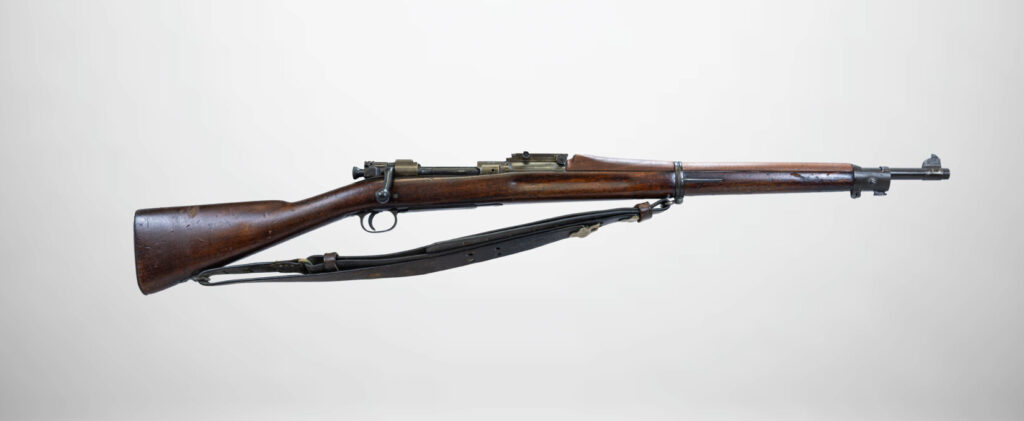 Studio shot of a wooden-stocked Springfield M1903 bolt-action rifle with a sling.