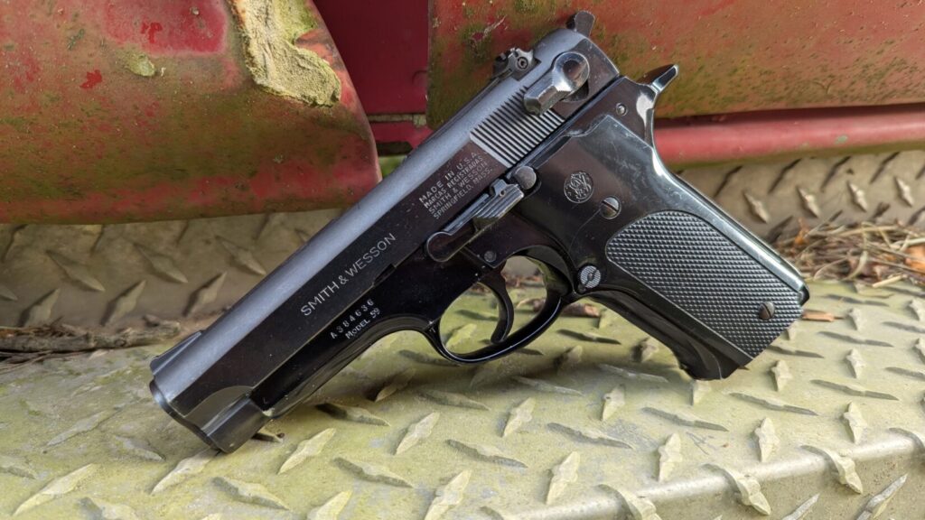 Close-up of the Smith & Wesson Model 59 pistol on a rusty metal diamond plate, clearly showing the "SMITH & WESSON" and "Model 59" roll marks.