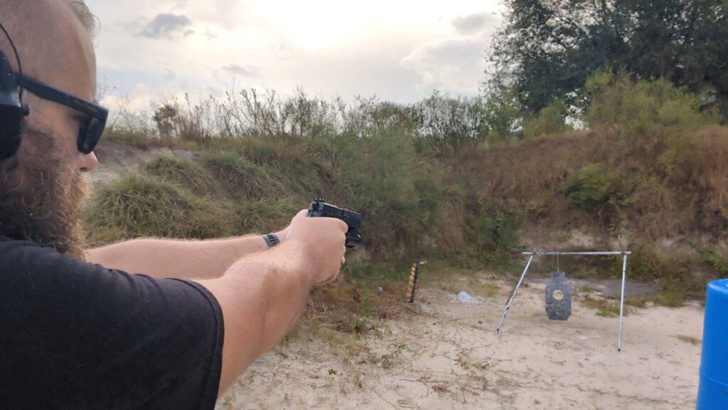 Close-up over the shoulder shot of a shooter aiming at a steel target.