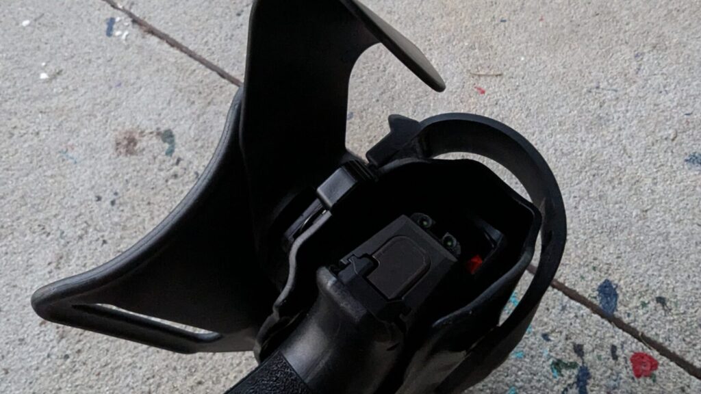 Close-up of the retention area of a black holster with a handgun inside.