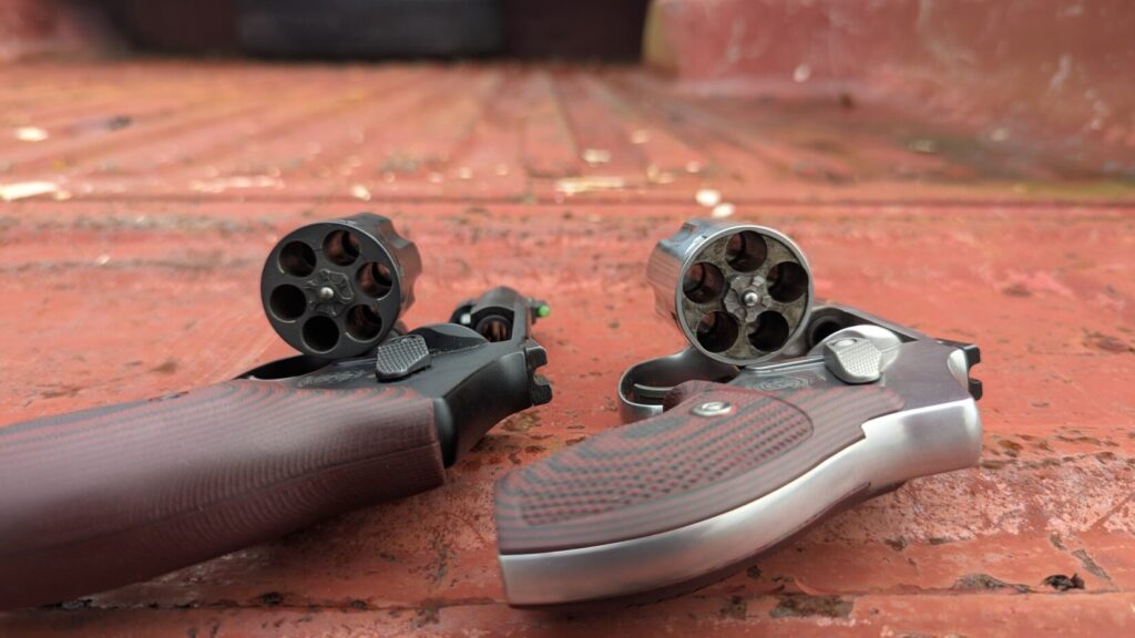 S&W 940 and S&W 432 UC revolvers with their cylinders open, lying on truck bed