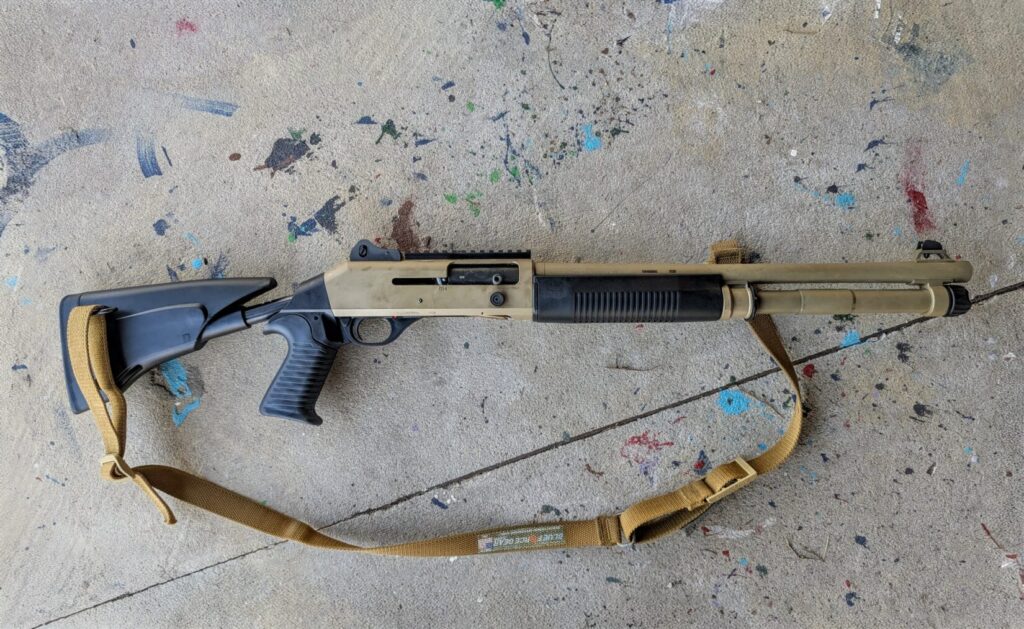Full view of the Benelli M4 shotgun on a paint-splattered concrete floor