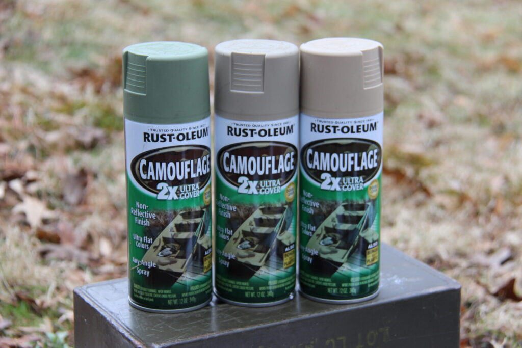 Three cans of spray paint on top of an ammo can.