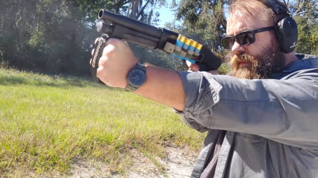 Man firing shotgun, showing shooting stance and foregrip.