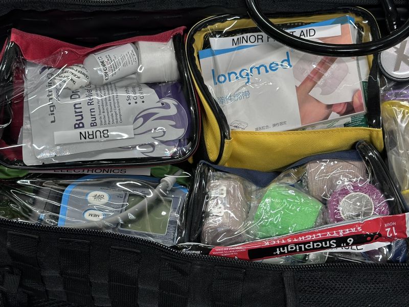 Four small clear bags with medical supplies in them, all placed in a larger backpack. 