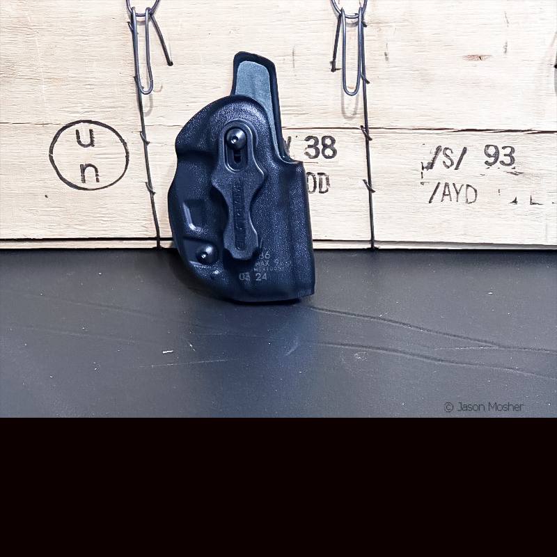 A black holster leaning up against a wooden box. 