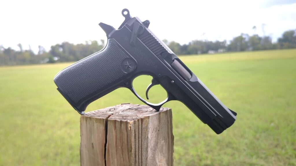 Star 30M pistol sitting on a wooden post outdoors, green field background.