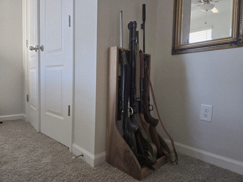 A wooden firearms rack in a room with rifles and shotguns.