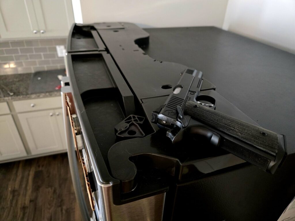 A 1911 pistol on top of a refrigerator in a kitchen