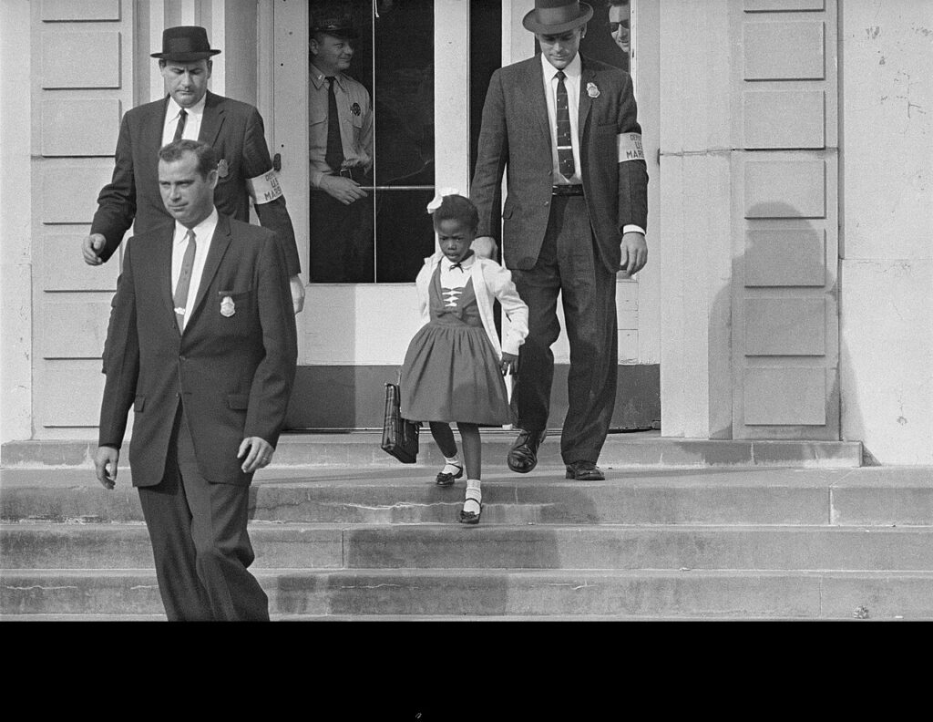 U.S. Marshals escorting Ruby Bridges, both to and from the William Frantz Elementary School in New Orleans in 1960, while segregationist protests continued.