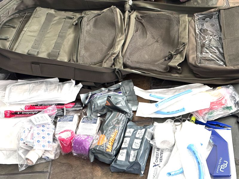 A bag and medical supplies laid out on a table. 