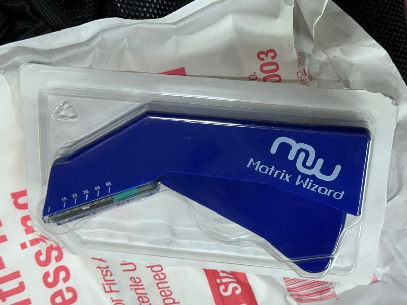 A blue wound staple gun still in the package. 
